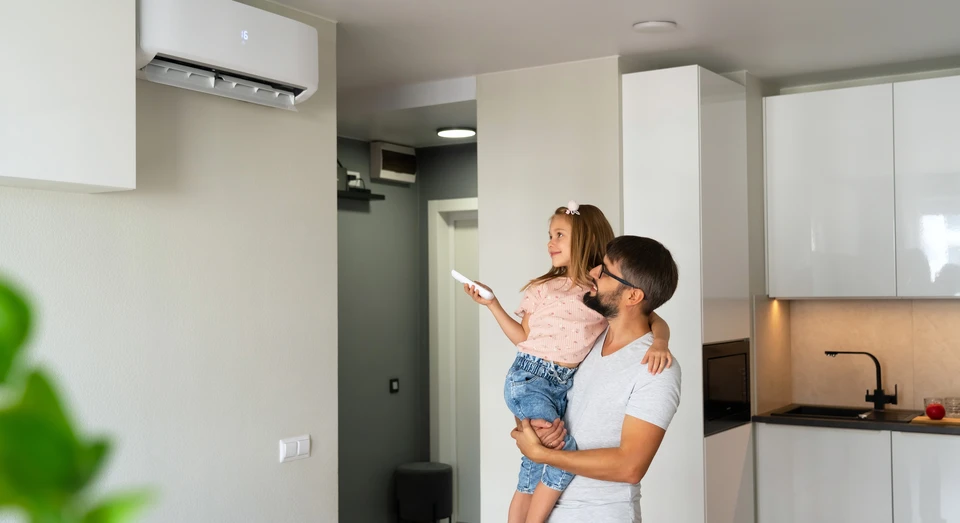 Père et petite fille allument l'air conditionné à l'aide d'une télécommande